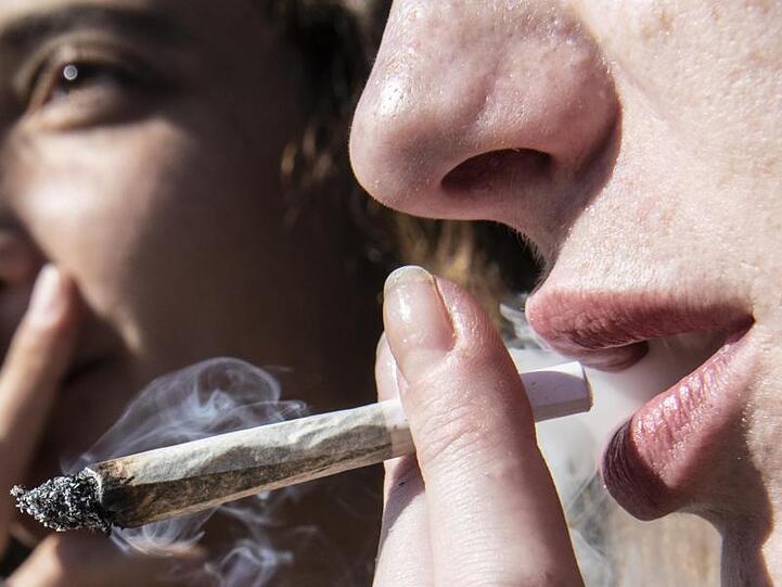 Zwei Frauen rauchen bei einer Protestaktion für legalen Cannabis-Konsum einen Joint. Foto: Paul Zinken/Archivbild