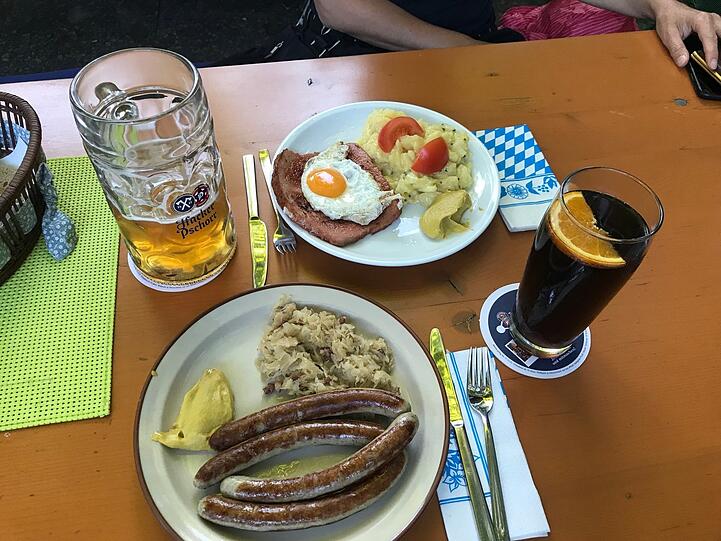 Zwei Paar Schweinswürscht mit Sauerkraut, Leberkäs mit Ei und Kartoffelsalat, eine Radler-Maß und ein Spezi - zusammen für 25 Euro.