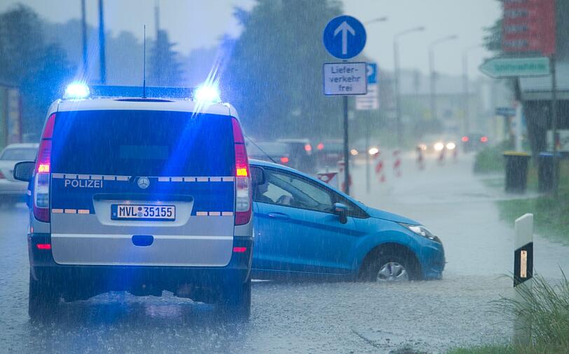 Bei starkem Regen steht ein Auto auf der überschwemmten B111 in Zinnowitz auf der Insel Usedom (Mecklenburg-Vorpommern).