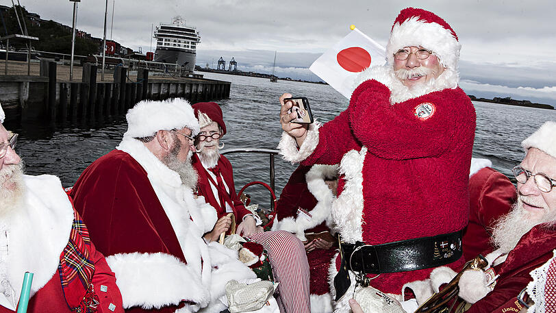 Ein japanischer Weihnachtsmann macht in der Nähe der Kleinen-Meerjungfrau-Bronzefigur im Hafen von Kopenhagen ein Selfie.