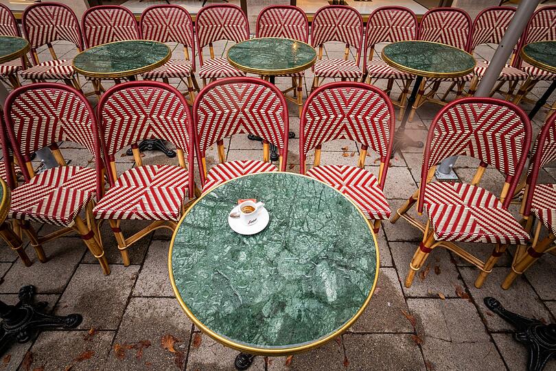 Eine Espresso-Tasse steht auf dem regennassen Tisch eines Cafés in der Innenstadt.