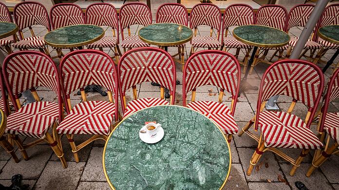 Eine Espresso-Tasse steht auf dem regennassen Tisch eines Cafés in der Innenstadt.