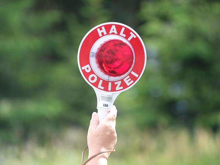 Eine Polizistin hält während einer Polizeikontrolle eine rote Winkerkelle in die Höhe. Foto: Sebastian Willnow/zb/dpa/Symbolbild