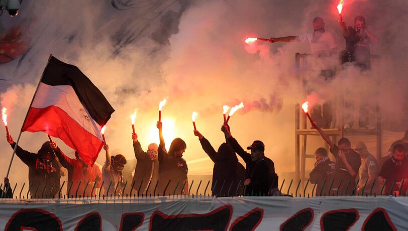 Fanatiker unter sich: Polnische Ultras zünden Pyrotechnik, einer trägt eine Flagge mit den Farben der Reichskriegsflagge.