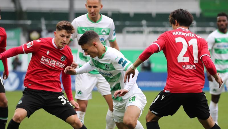 Fürths Branimir Hrgota (M) kämpft mit Florent Muslija (l) und Sei Muroya (r) von Hannover 96 um den Ball.