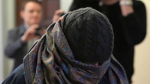 Eine Zeugin verl&auml;sst vermummt den Gerichtssaal.
