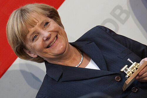 Die Bundeskanzlerin als Bahnfan: Angela Merkel hält eine kleine, vergoldete Modell-Lokomotive in der Hand.