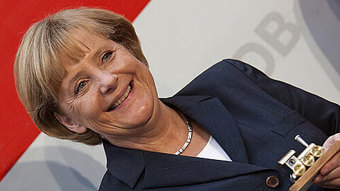 Die Bundeskanzlerin als Bahnfan: Angela Merkel hält eine kleine, vergoldete Modell-Lokomotive in der Hand.