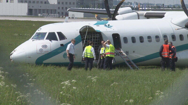 Mitarbeiter des Flughafens in München betrachten die Maschine der italienischen Fluggesellschaft, die am Donnerstag auf dem Münchner Flughafen notlanden musste. Das Flugzeug mit 62 Menschen an Bord hatte kurz nach dem Start in Richtung Venedig umdrehen müssen, weil sich Rauch in der Kabine entwickelt hatte. Bei der Landung wurden fünf Personen leicht verletzt, die Maschine kam neben der Landebahn zum Stehen.