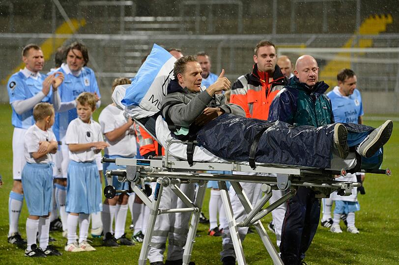 Olaf Bodden wird auf einem Krankenbett auf den Rasen des Grünwalder Stadions gefahren.
