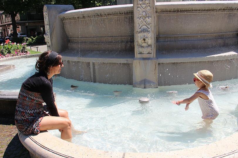 Erfrischung mitten in der Stadt: am Brunnen auf dem Weißenburger Platz zieht es Monika und Tochter Mia ins Wasser.