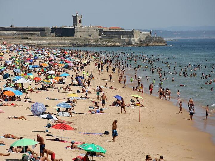 Strandbesucher an einem heißen Nachmittag am Strand Carcavelos.