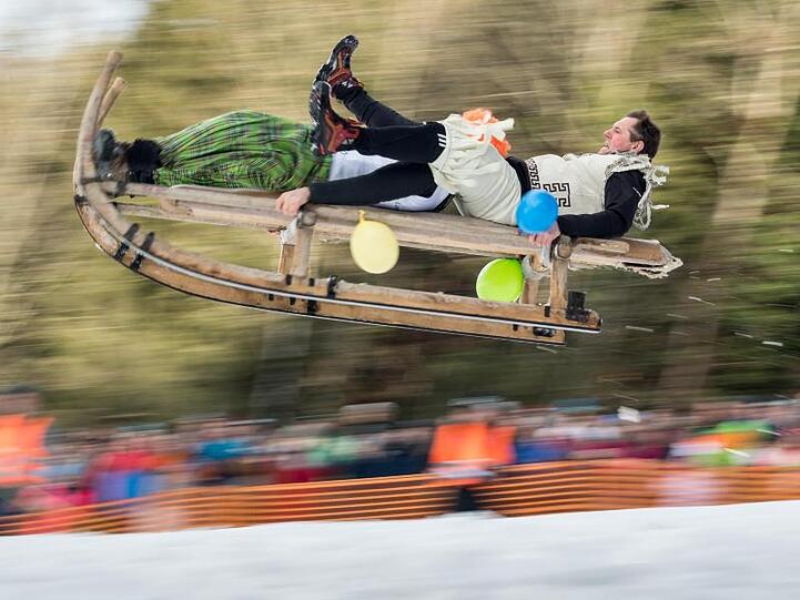 Ein Schnabel-Schlitten mit 2 Personen als Besatzung springt im Zielbereich an den Zuschauern vorbei. Foto: Peter Kneffel