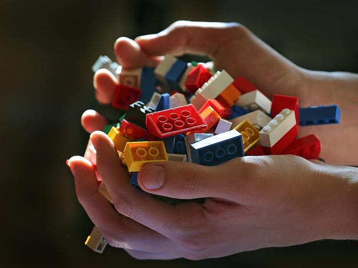Zwei Hände halten verschiedene Lego-Steine. Foto: Karl-Josef Hildenbrand/Archiv