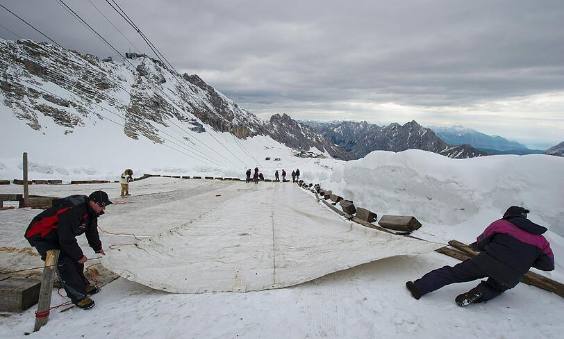 Arbeiter decken auf dem Zugspitzplatt bei Grainau den Gletscher mit einer Plane ab, um ein Abschmelzen zu verhindern. Deutschlands einziger Gletscher soll waehrend der warmen Sommermonate mit der 500 bis 600 Quadratmeter grossen Plane vor Sonne und Regen geschuetzt werden.