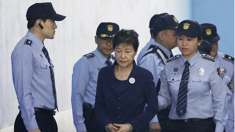Die frühere Präsidentin von Südkorea wird von Polizisten zum Beginn ihres Prozesses zum Gericht begleitet.