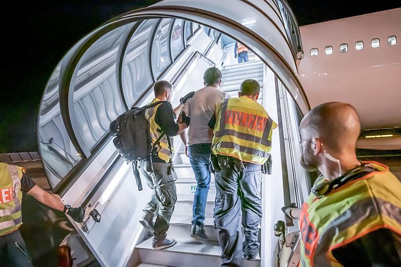 Polizeibeamte begleiten einen Afghanen in ein Charterflugzeug.