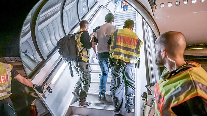 Polizeibeamte begleiten einen Afghanen in ein Charterflugzeug.