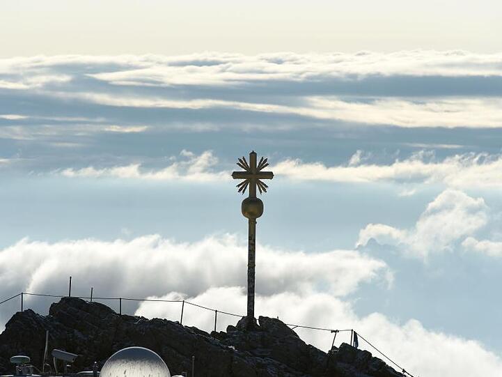 Vom Turm der Wetterstation der Zugspitze ist das Gipfelkreuz von Deutschlands höchstem Berg zu sehen. Foto: Felix Hörhager/Archivbild