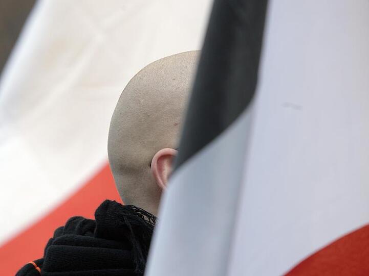 En Mann mit geschorenem Kopf zwischen schwarz-weiß-roten Fahnen: Momentaufnahme einer Demo.