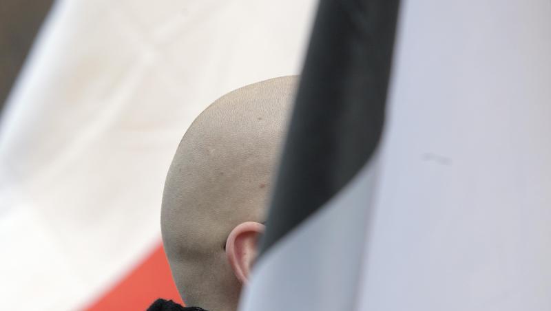 En Mann mit geschorenem Kopf zwischen schwarz-weiß-roten Fahnen: Momentaufnahme einer Demo. En Mann mit geschorenem Kopf zwischen schwarz-weiß-roten Fahnen: Momentaufnahme einer Demo.