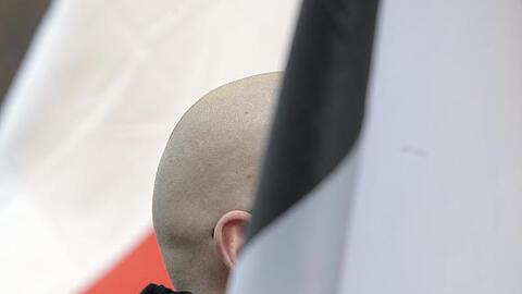 En Mann mit geschorenem Kopf zwischen schwarz-weiß-roten Fahnen: Momentaufnahme einer Demo.
