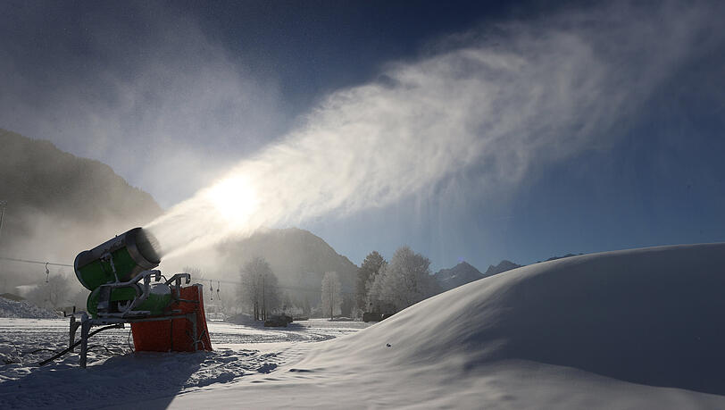 Eine Schneekanone produziert an einer Skipiste am Fuß des Tegelberges bei Schwangau Schnee.