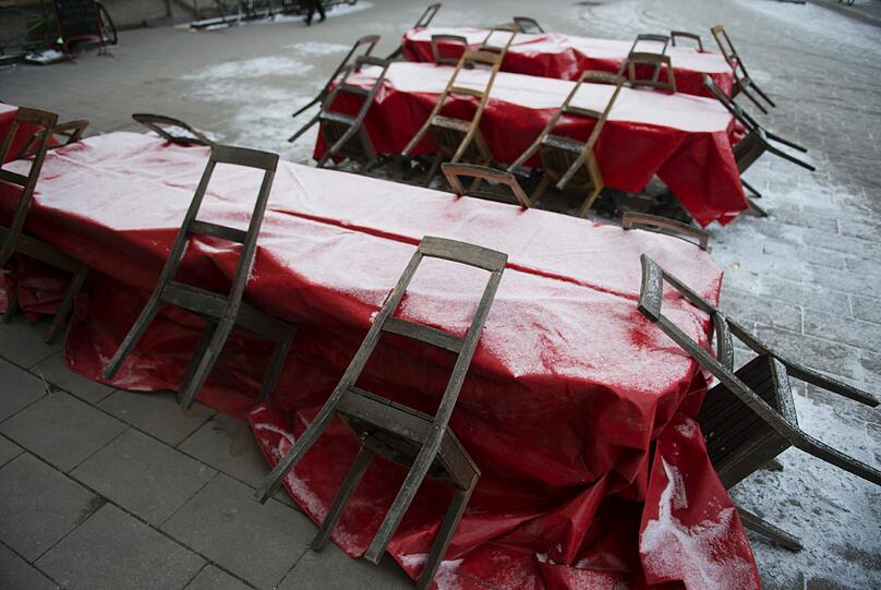 Eine hauchzarte Schneedecke bedeckt am Dienstag (15.01.13) in Muenchen die Abdeckplanen von Tischen in einem Strassencafe.