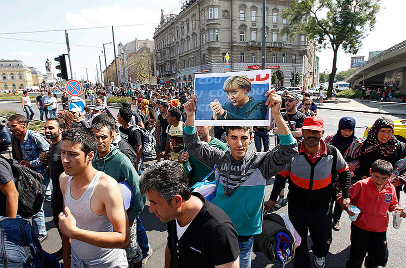 Flüchtlinge vor dem Keleti-Bahnhof in Budapest halten am 04. September 2015 ein Bild von Bundeskanzlerin Angela Merkel (CDU) hoch.