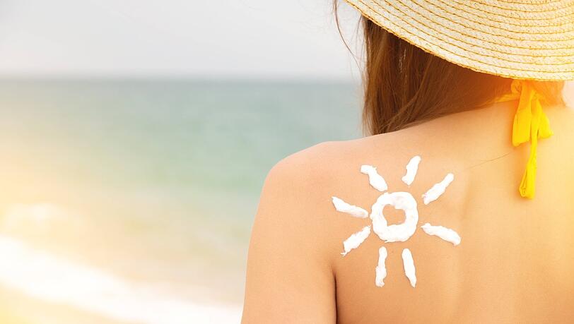 Eine Frau mit einer Sonne aus Sonnencreme auf ihrer Schulter.