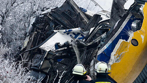 Einsatzkräfte stehen am Wrack einer Lokomotive Einsatzkräfte stehen am Wrack einer Lokomotive