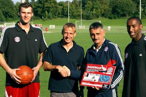 Fußball-Chefcoach Jürgen Klinsmann (2.v.l.) bekommt von Stuart Robbins, Georg Kämpf und Tim Morris (v.l.) die Dauerkarte.