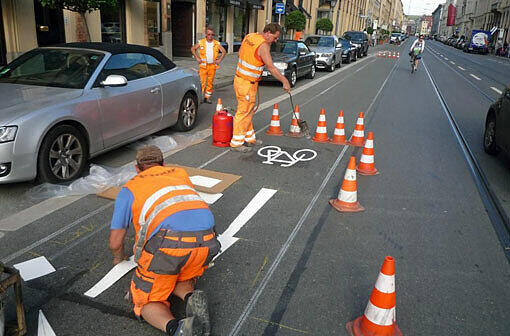 In der Maximilianstraße malen Arbeiter des Baureferats die neue Markierung für den Radlstreifen auf die Fahrbahn.