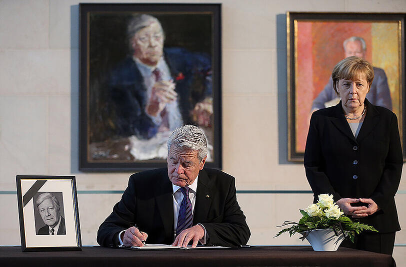 Bundespräsident Joachim Gauck trägt sich ins Kondolenzbuch ein. Rechts: Bundeskanzlerin Angela Merkel (CDU).