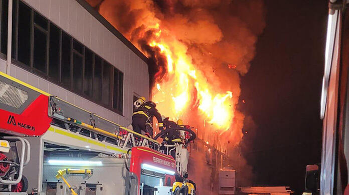 Flammen und eine enorm große giftige Qualmwolke steigen in den Nachthimmel über Feldmoching auf. Foto: Branddirektion