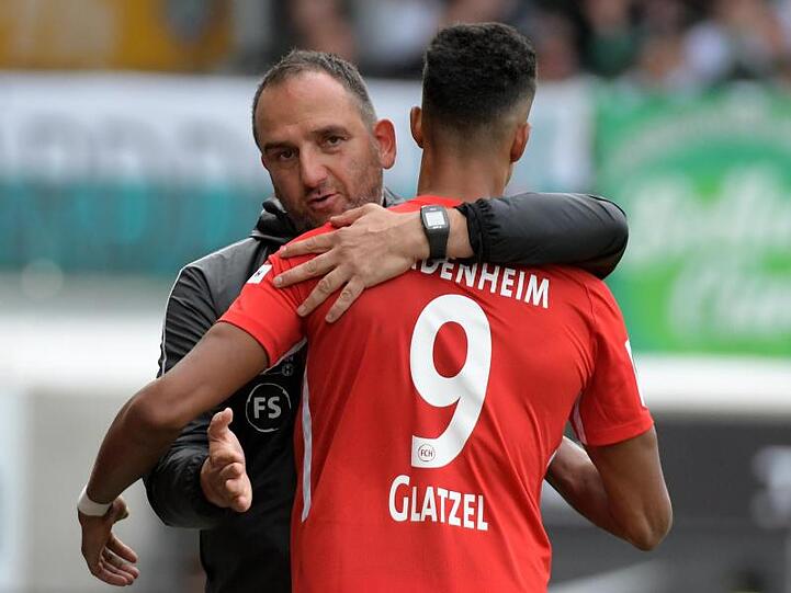 Heidenheims Trainer Frank Schmidt (l) umarmt Robert Glatzel vor dessen Einwechselung. Foto: Stefan Puchner/Archiv