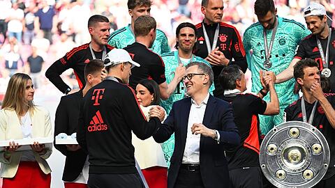 Bayerns Trainer Thomas Tuchel (Mitte l) wird von Jan-Christian Dreesen zum Gewinn der 33. deutschen Meisterschaft gratuliert.