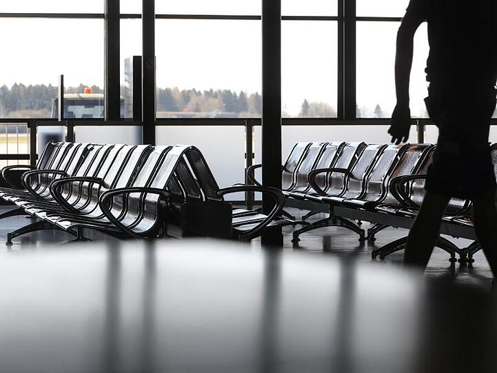 Ein Mitarbeiter läuft vor leeren Stuhlreihen. Foto: Karl-Josef Hildenbrand/dpa