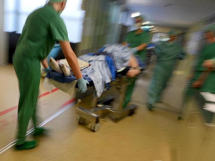 Ein Mediziner-Team fährt in einer Klinik nach einer Operation einen Patienten im Bett durch den Klinikflur. Foto: Felix Kästle/Archiv