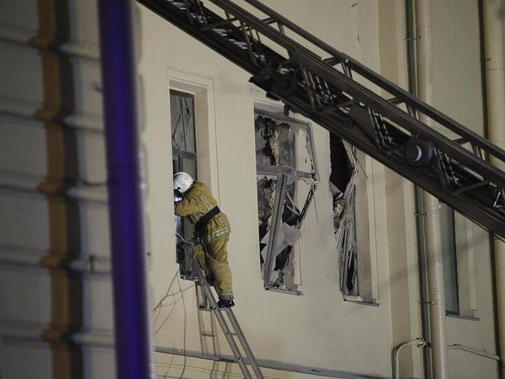 Ein Feuerwehrmann steigt durch ein Fenster in ein Gebäude der St. Petersburger Universität.