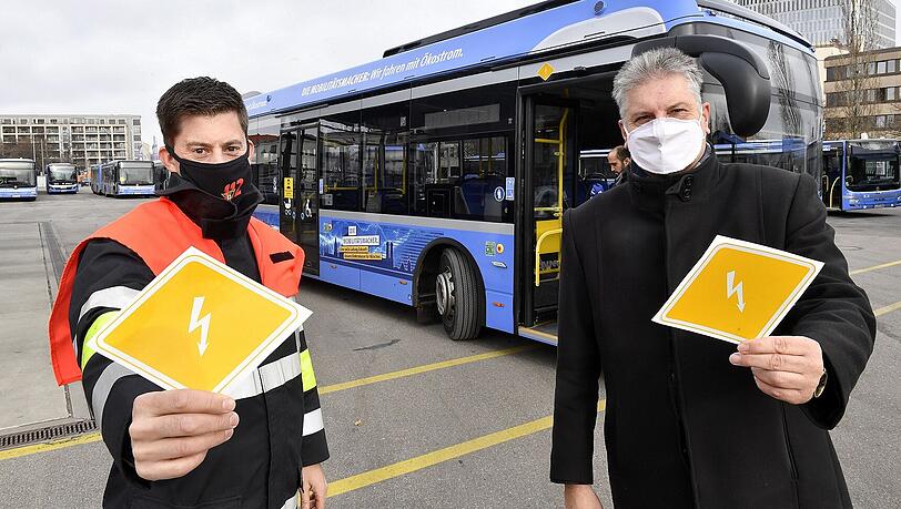 Michael Gaertner, Ausbildungsleiter "Technische Unfallrettung" an der Feuerwehr- und Rettungsdienstschule der Feuerwehr München (l.) und MVG-Buschef Veit Bodenschatz präsentieren die Kennzeichnungen für E-Busse.