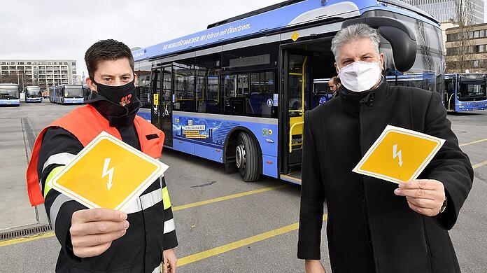 Michael Gaertner, Ausbildungsleiter "Technische Unfallrettung" an der Feuerwehr- und Rettungsdienstschule der Feuerwehr München (l.) und MVG-Buschef Veit Bodenschatz präsentieren die Kennzeichnungen für E-Busse.