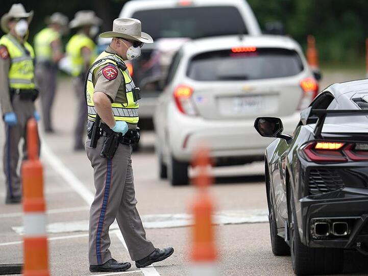 Polizisten kontrollieren kontrollieren Autofahrer bei der Einreise von Louisiana nach Texas, um zu überprüfen, ob diese sich in eine 14-tägige Selbstquarantäne begeben müssen.