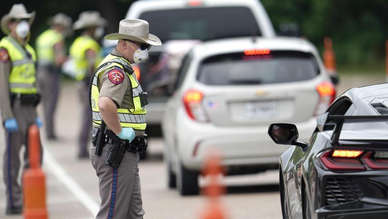 Polizisten kontrollieren kontrollieren Autofahrer bei der Einreise von Louisiana nach Texas, um zu überprüfen, ob diese sich in eine 14-tägige Selbstquarantäne begeben müssen. Polizisten kontrollieren kontrollieren Autofahrer bei der Einreise von Louisiana nach Texas, um zu überprüfen, ob diese sich in eine 14-tägige Selbstquarantäne begeben müssen.
