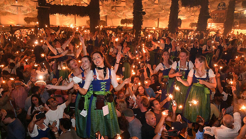 Bedienungen und Gäste feiern mit Wunderkerzen beim traditionellen Kehraus im Hofbräuzelt den Abschluss der Wiesn.