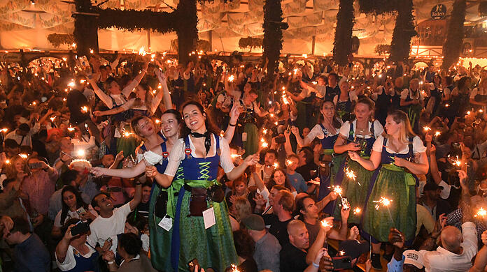 Bedienungen und Gäste feiern mit Wunderkerzen beim traditionellen Kehraus im Hofbräuzelt den Abschluss der Wiesn.