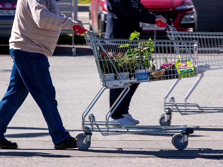 Kunden verlassen mit vollen Einkaufswagen einen wieder eröffneten Bau- und Gartenmarkt. Foto: Jens Büttner/dpa-Zentralbild/dpa