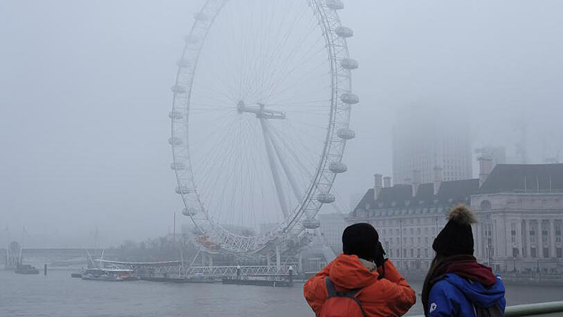 Touristen fotografieren das in Nebel gehüllte London Eye. In Großbritannien ist der Tourismus leicht zurück gegangen.