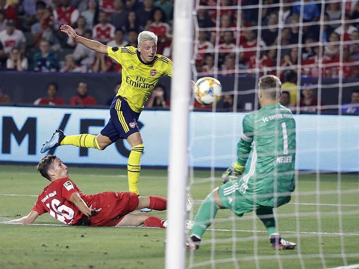 Münchens Jonas Kehl (l) und Torhüter Manuel Neuer (r) gegen Arsenals Mesut Özil. Foto: Marcio Jose Sanchez
