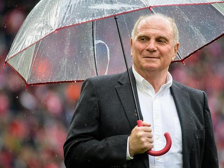 Uli Hoeneß, Vereinspräsident von FC Bayern, steht vor Spielbeginn mit einem Regenschirm im Stadion. Foto: Matthias Balk/Archivbild